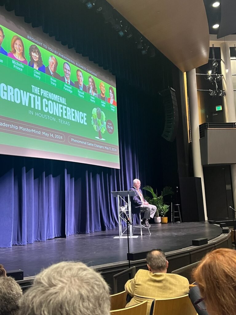 Speaker lineup screen for The Phenomenal Growth Conference in Houston, naming Michelle Prince alongside Brian Tracy and Howard Partridge.